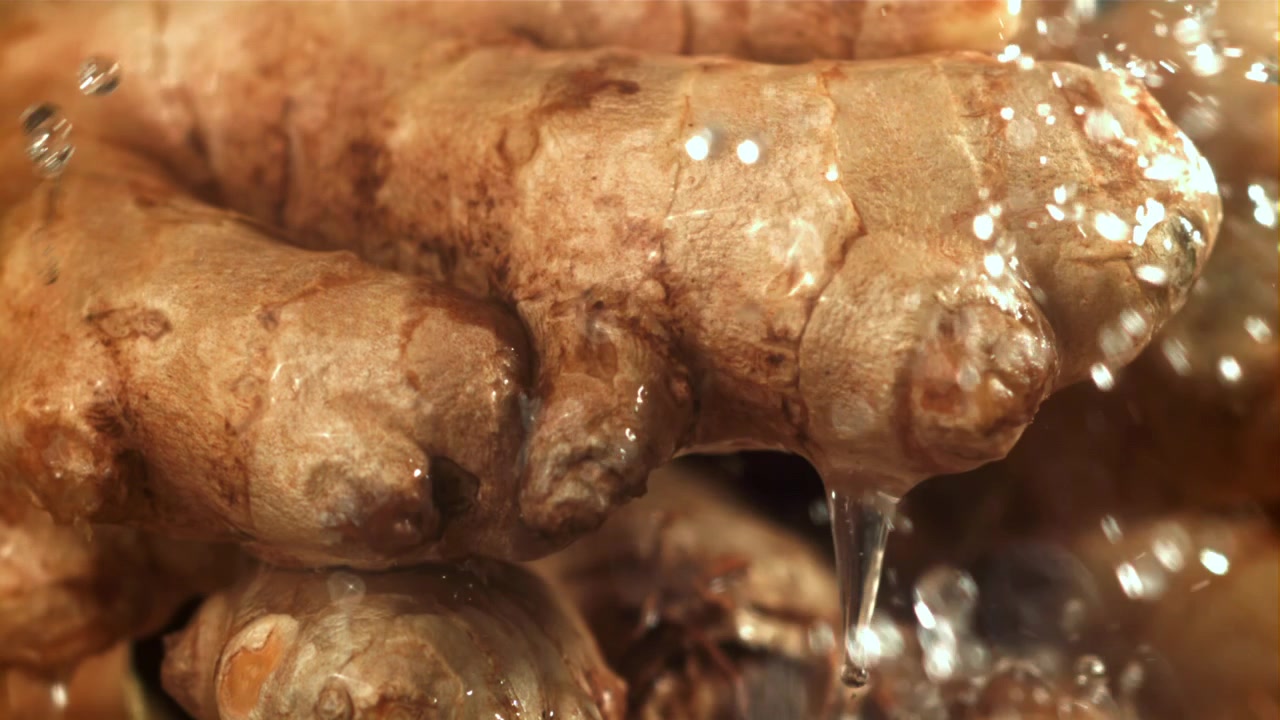 Zeitlupe Nahaufnahme: Frische Ingwerwurzel wird von Wasser gewaschen.