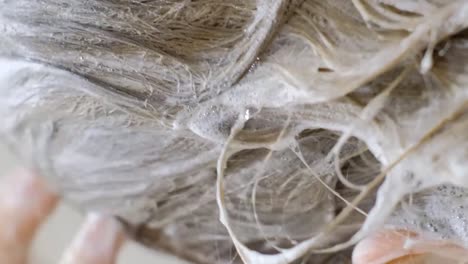close-up of a blonde washing her hair. white foam from shampoo on long hair. head hair care. vertical video