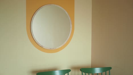 una habitación con un espejo y sillas verdes.