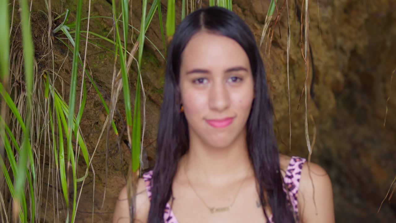 A tight shot of a woman's face reveals her joy as she embraces the sun and sea in a thong bikini