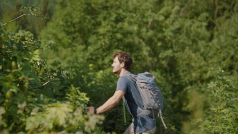 a young hiker walking on a path with hiking poles surrounden with high green bushes and trees