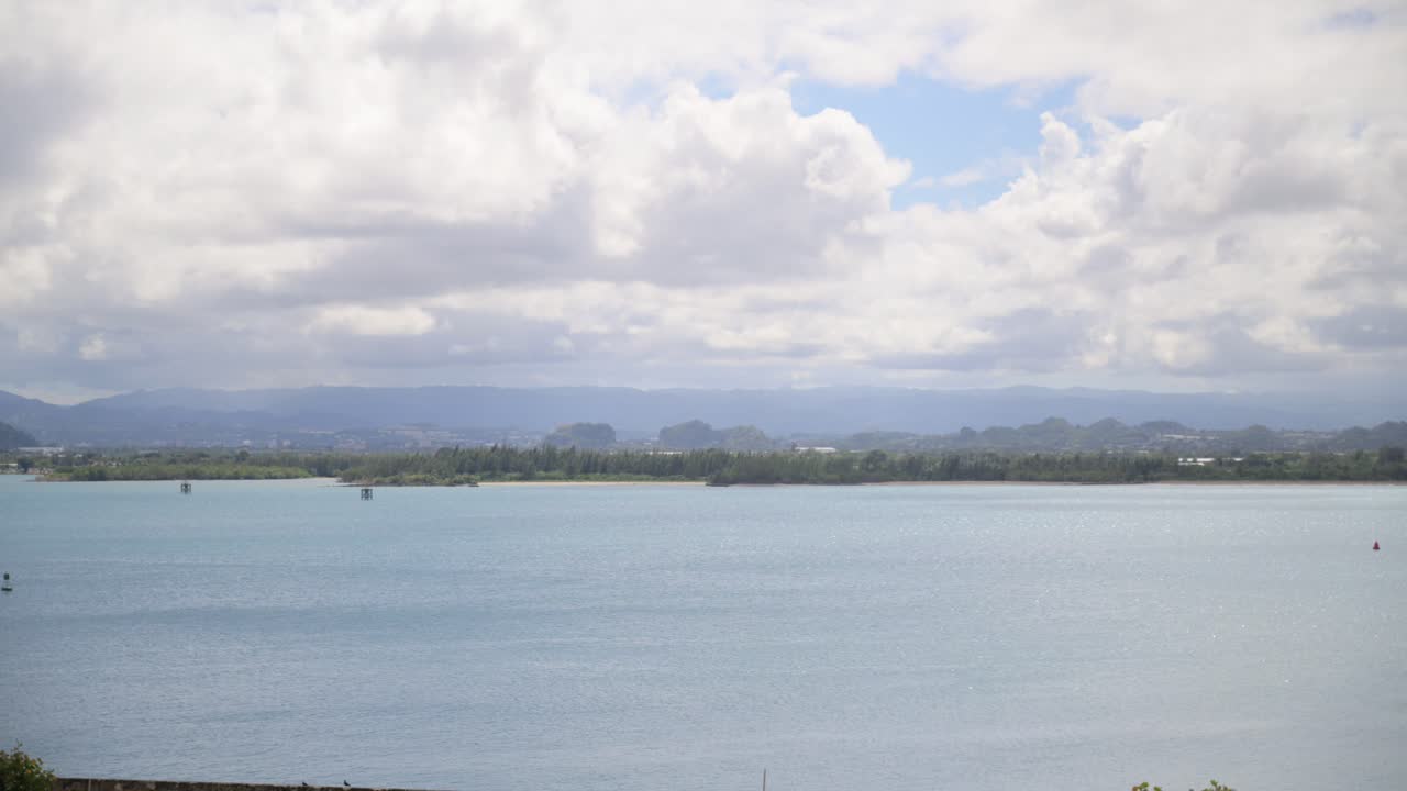 Ocean water with mountains off in the distance. Cloudy day.
