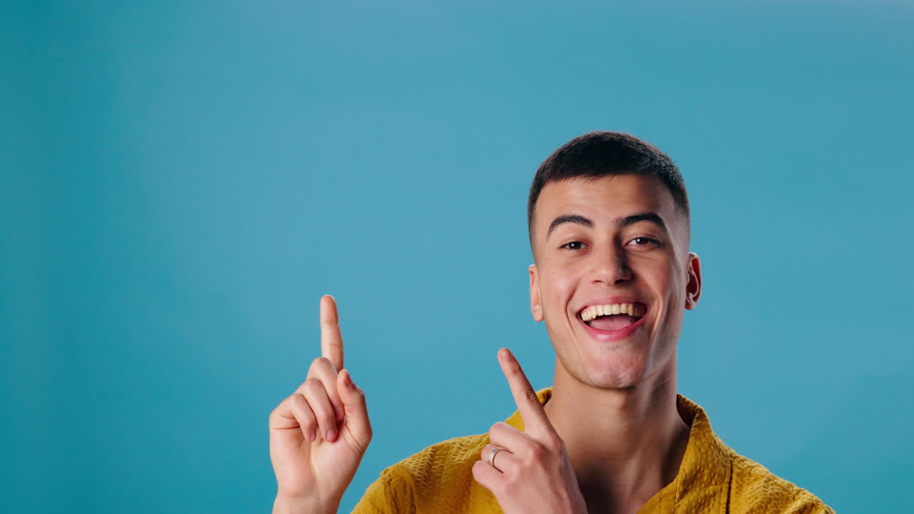 Excited man pointing upwards with a light blue background