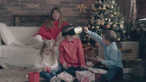 young-woman-sits-on-sofa-children-play-and-open-presents