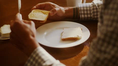 hombre comiendo tostadas con mantequilla y queso crema