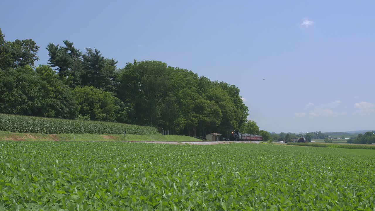 여름날 아미쉬 시골을 따라 연기를 내뿜는 여객열차가 있는 1924년 증기기관