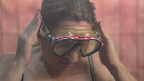 a female diver puts on her diving mask, preparing for an exciting underwater adventure. the setting exudes anticipation and readiness, capturing the moment prior to exploration