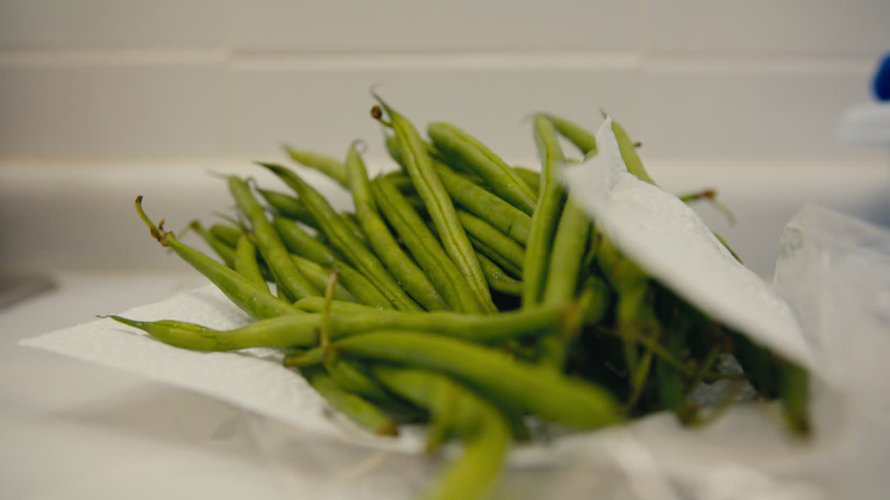 Fresh green beans on paper towel in a kitchen, with slow cinematic push-in and soft fluorescent light