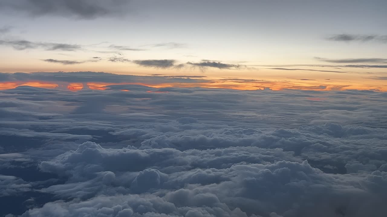 Sunset view shot from an airplane overflying a layer of clouds flying westbound at 12000m high