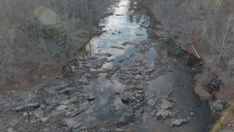 Hoher-Winkel-Auf-Einem-Felsigen,-Ominösen-Fluss,-Der-Im-Herbst-In-Einem-Blattlosen-Wald-Stagniert