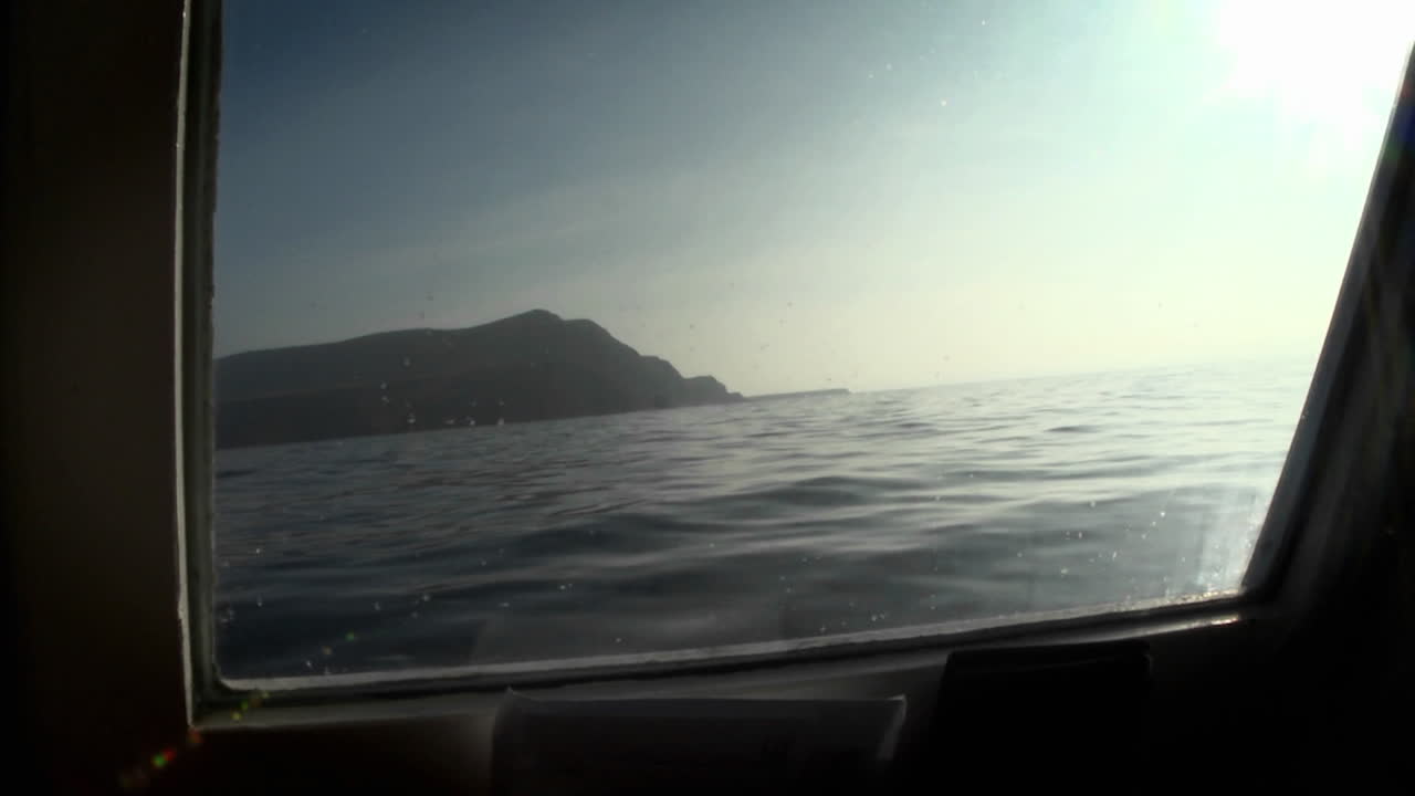 Uma ilha é vista através da vigia de um barco