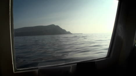 An-island-is-viewed-through-the-porthole-of-a-boat