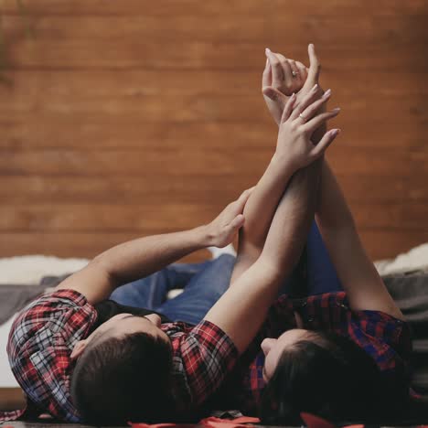 beautiful enamored couple are touching by each other's hands in the bedroom on saint valentine's day