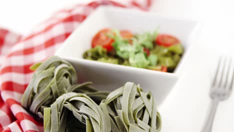 Fresh-spinach-fettuccine-noodles-and-bowl-of-salad-on-table