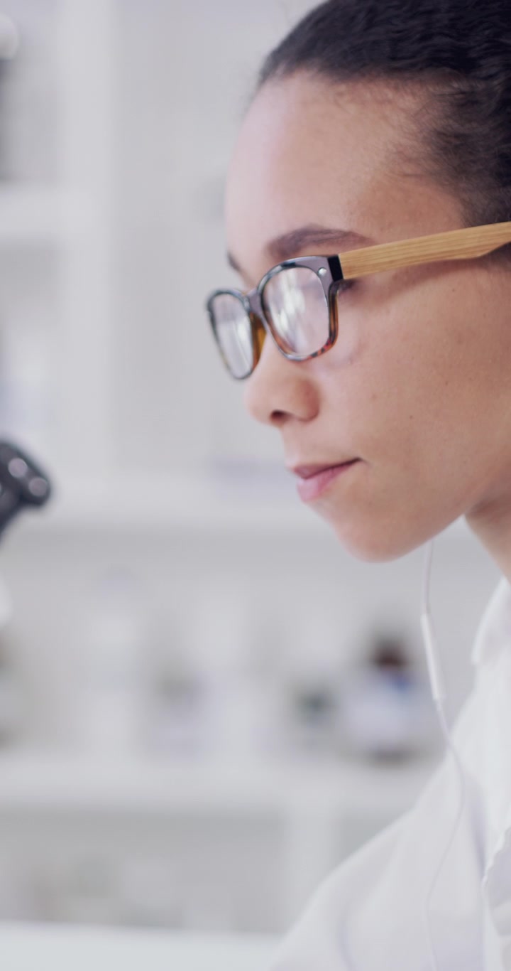 Scienziata che esamina campioni al microscopio in laboratorio