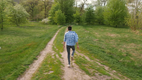 hombre caminando por un camino de campo a través de un bosque de primavera