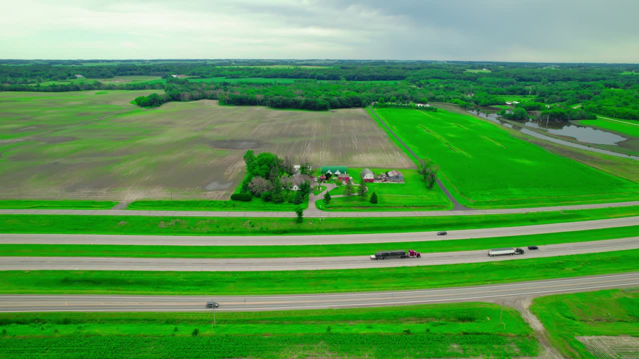 Aerial view following a red flatbed truck with a load covered in black tarps, driving along an interstate highway in a rural area. Minneapolis, Minnesota, USA