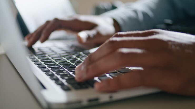 Nahaufnahme: Mann tippt auf Laptop-Tastatur in der Wohnung. Hände drücken Tasten.