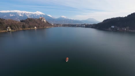 boat sailing on bled lake with alps at background