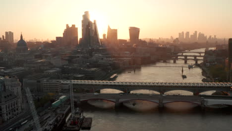 descending aerial shot of london skyscrapers at sunrise from the river thames