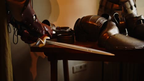 Close-up-of-plastic-sword-being-cleaned-in-medieval-armory-by-a-knight