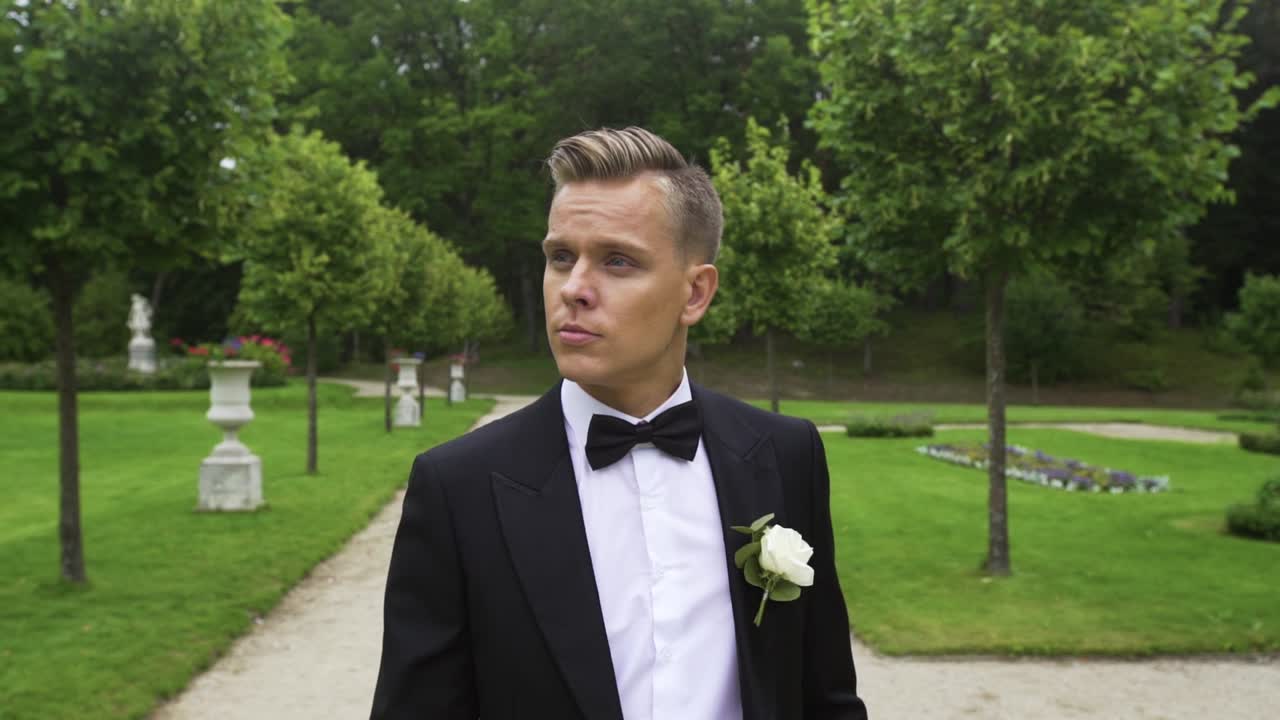 joven europeo confiado y guapo camina en el hermoso parque verde, feliz y sonriente