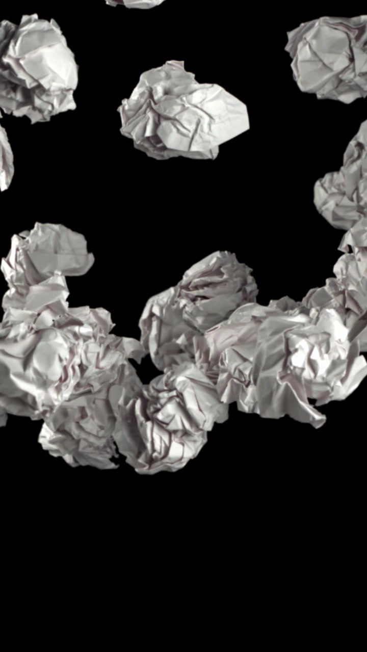 Palline di carta bianca accartocciata che fluttuano verso l'alto su sfondo nero