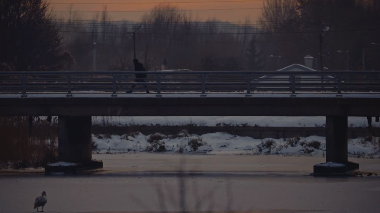 man crossing over a bridge above frozen cold lake at snowy winter Gdansk Poland