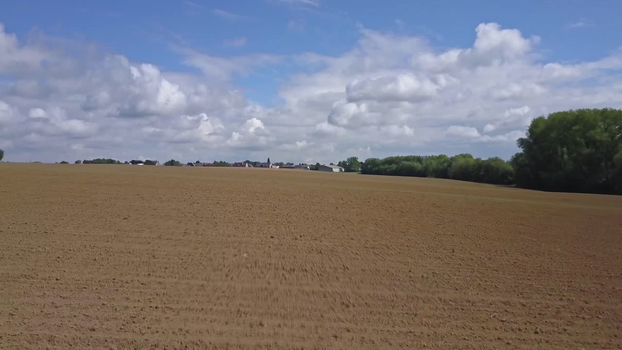 Rückwärtsflug einer Drohne in Richtung einer Stadt, über den Feldern