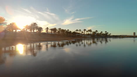 Aerial-view:-sunset-reflecting-over-Spanish-golf-club-lake-and-palm-trees