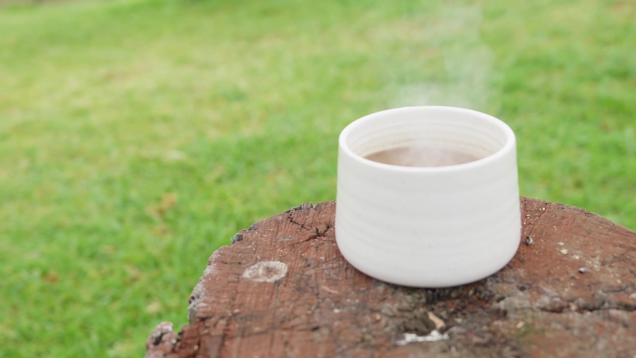 Hot cup of coffee steaming on a log outdoors. Peaceful nature scene capturing warmth, relaxation, camping, adventure and enjoying a fresh coffee in the Australian bush.