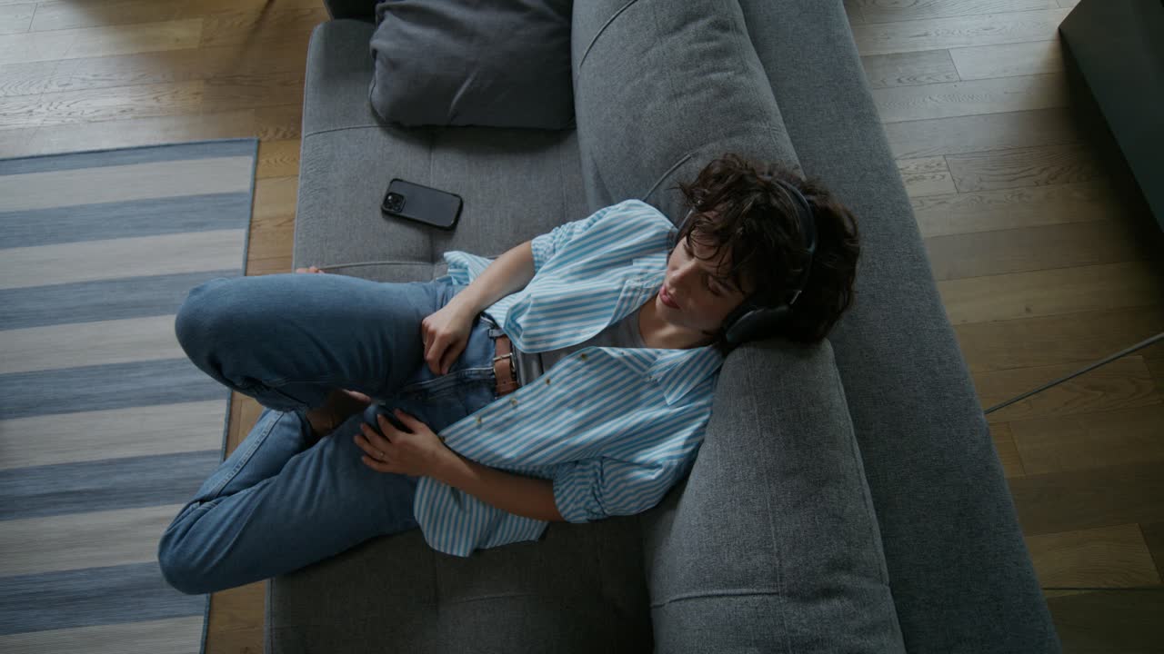 mujer relajándose en el sofá con auriculares