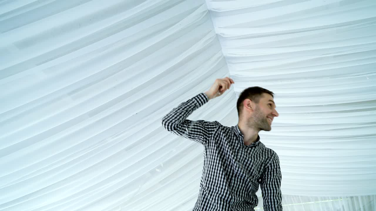 hombre colgando guirnaldas de linternas blancas en el techo.