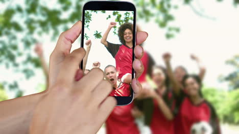 hand showing girls playing football clips on smartphone