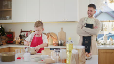 dad is proud of his son who cooks in the kitchen watching him