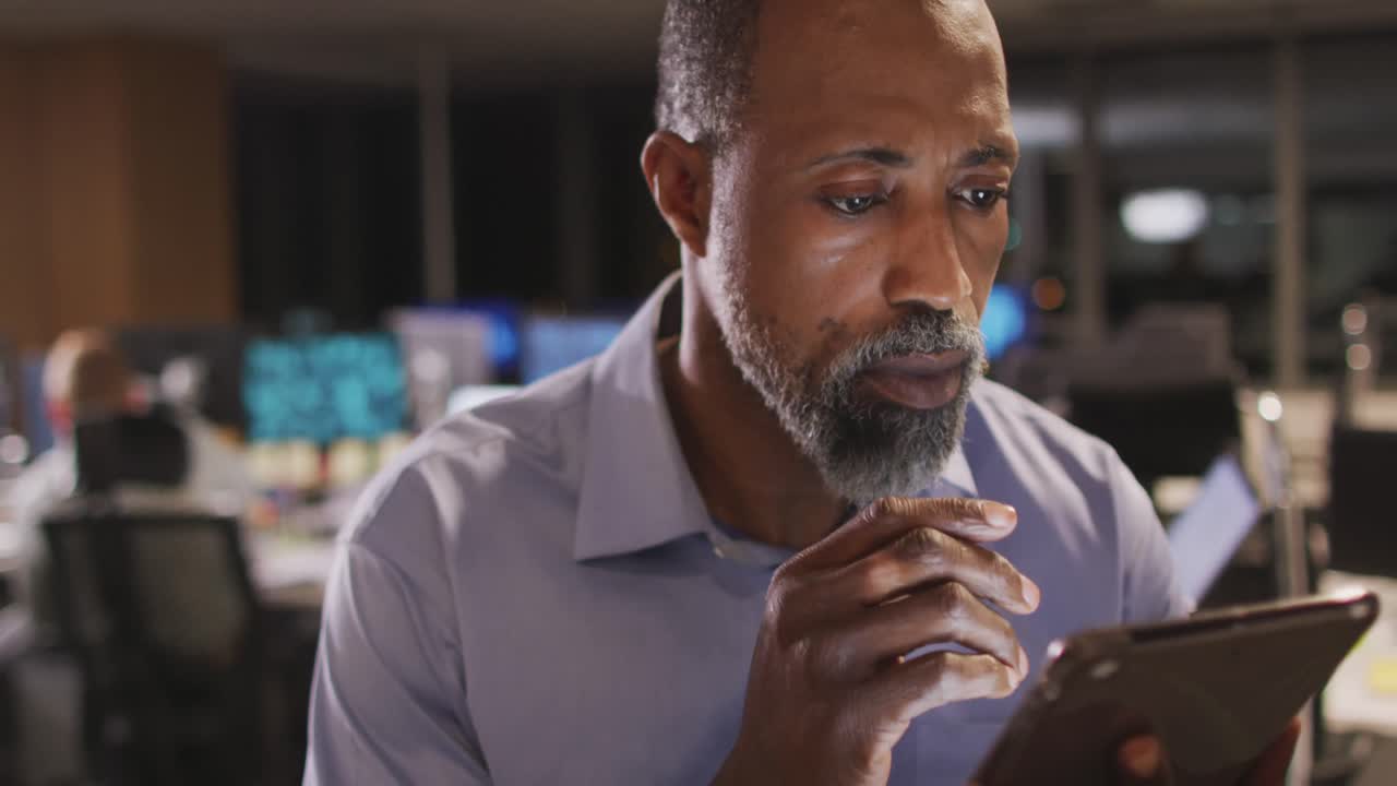 Thoughtful professional businessman using a digital tablet in modern office in slow motion