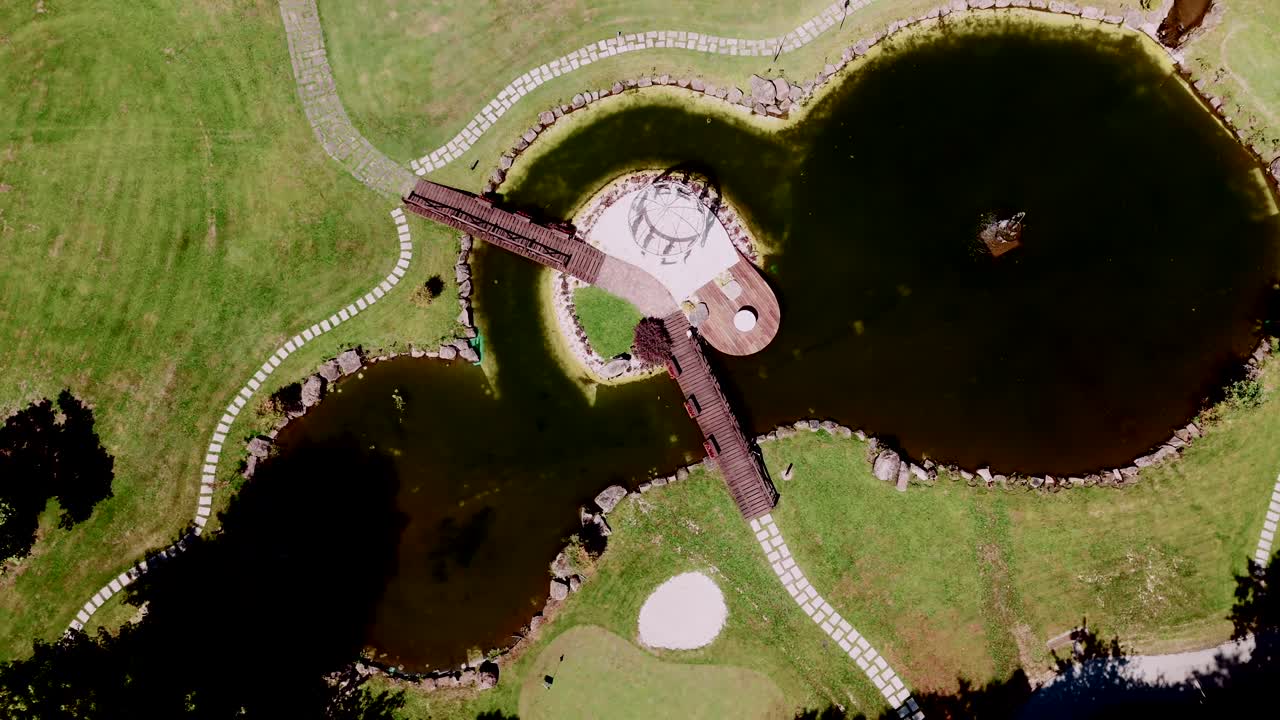Aerial view of a large lake with a bridge on a giant golf course surrounded by greenery