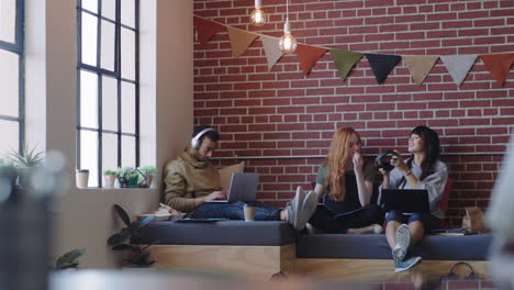 young diverse business students studying woman friends listening to music together wearing headphones enjoying working together in relaxed social workplace