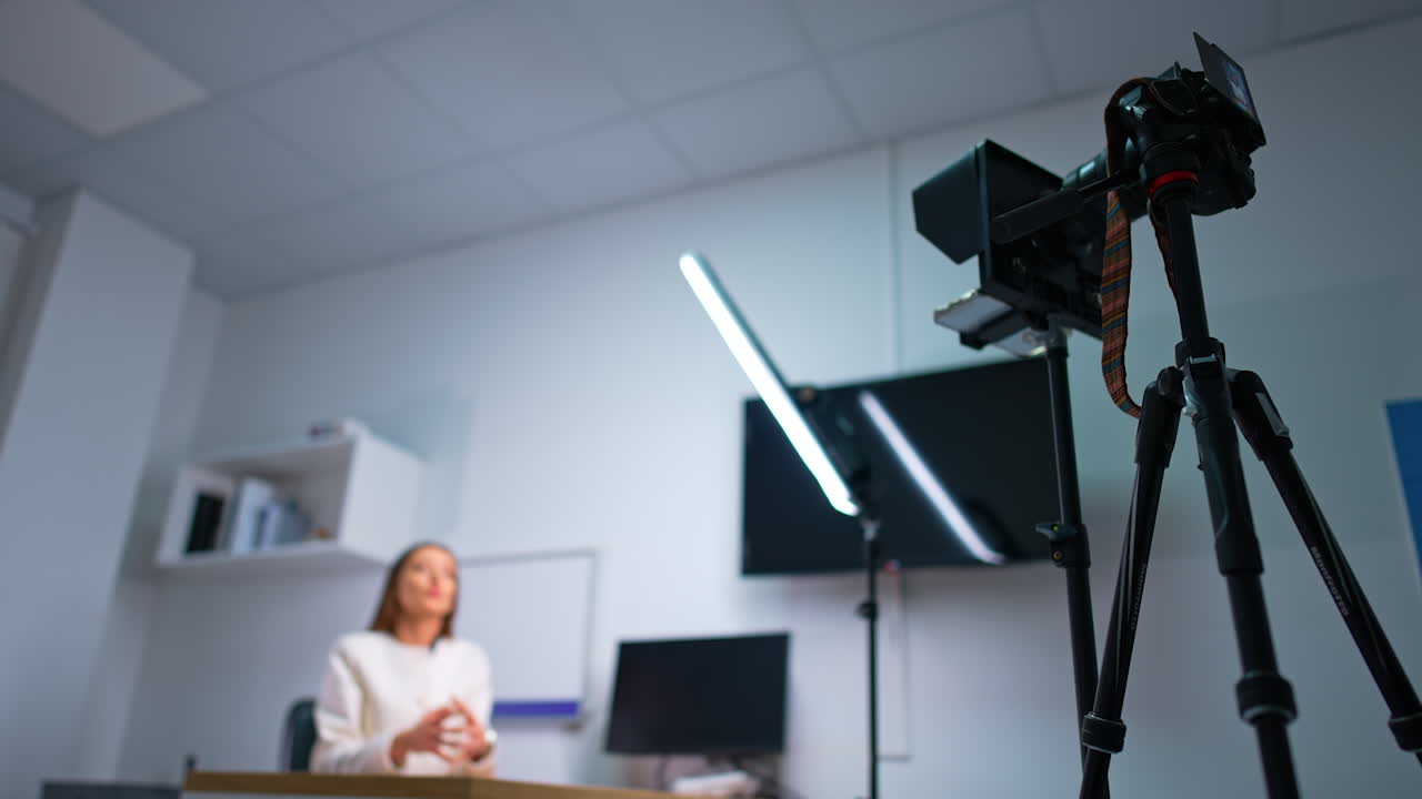 Professional camera on tripod and daylight lamp used for recording a blog. Female influencer takes video indoors. Blurred backdrop.