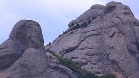 People-climb-the-tall-mountain-peaks-behind-Montserrat-Monastery-in-Spain