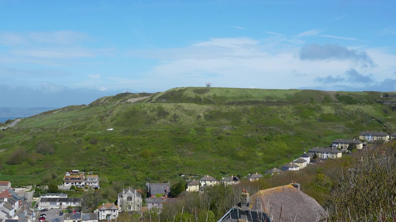 Un'ampia inquadratura panoramica delle dolci colline verdi e delle case residenziali a Weymouth e Portland, Dorset. Ideale per documentari di viaggio e contenuti per il turismo regionale