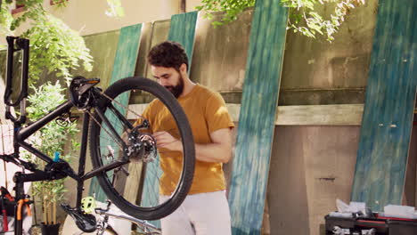 male cyclist mending bike wheel in yard