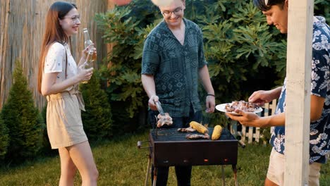 teenagers friends barbecuing at grill on summer patio