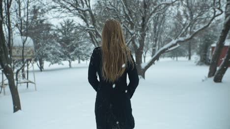 woman walking outside in slow motion, christmas winter snow as snowflakes fall in cinematic slow motion