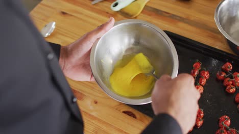 mixed race male chef mixing eggs in a bowl