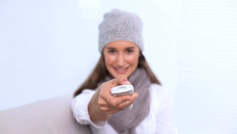 Smiling-young-woman-watching-television-and-changing-channel