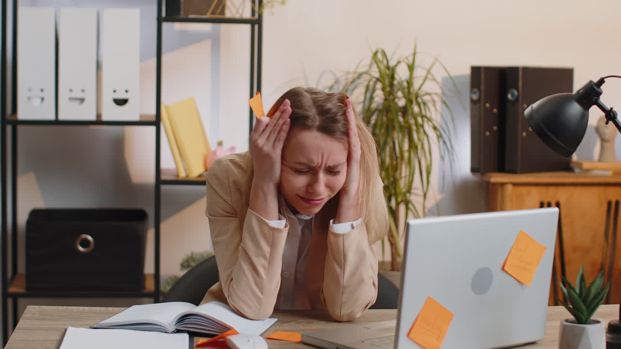 Tired sad exhausted businesswoman working on laptop at office with many sticker tasks panic attack