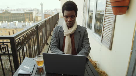 black man working on laptop on rooftop terrace