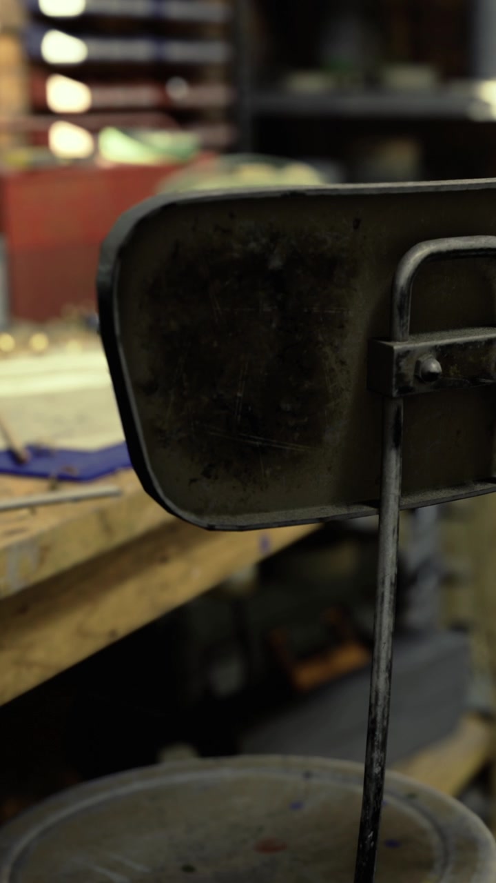 Metal chair back leaning on a workbench in a workshop space during daytime
