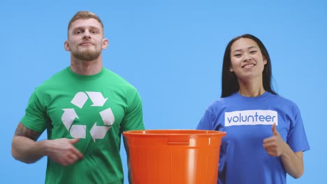hombre y mujer eco-conscientes poniendo botella en el cubo